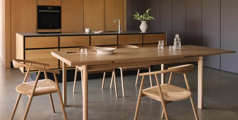 Wood dining table and woven chairs in a modern kitchen interior.