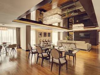 Elegant dining and living room with round upholstered chairs, dining table and wood cabinetry