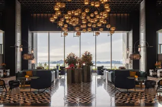 Luxury hotel lobby with lounge chairs, sofas, tables and clustered pendant lights