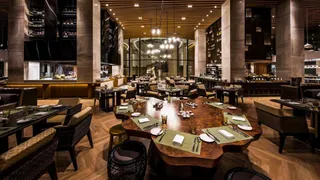 Modern restaurant with large irregular wooden dining table, chairs and banquette seating