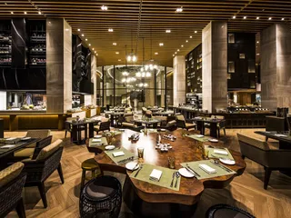Modern restaurant with wooden dining tables, woven chairs and banquette seating