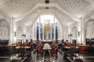 Large restaurant dining room with upholstered chairs, tables and decorative wall panels
