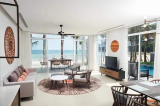 Bright coastal living room with sofa, lounge chairs, coffee table and wooden cabinetry