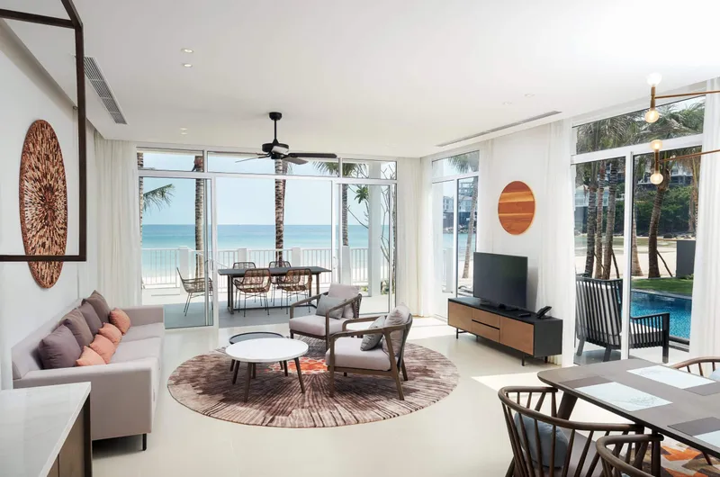 Bright coastal living room with sofa, lounge chairs, coffee table and wooden cabinetry