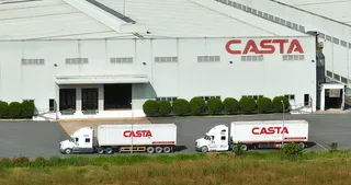 Factory exterior with CASTA signage and branded trucks