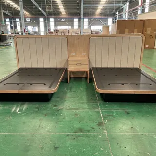 Two upholstered bed frames and a matching bedside unit in a factory