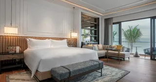 Hotel bedroom with upholstered bed, bench, seating and side tables