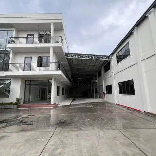 White multi-storey building beside a covered industrial courtyard on a wet day