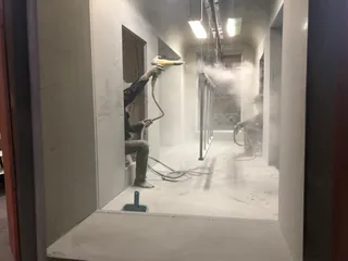 Worker spray-finishing furniture components inside a production booth