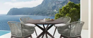 Woven outdoor dining chairs around a round wooden table