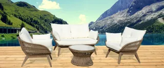 White-cushioned rattan sofa, armchairs and round coffee table on a deck