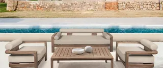Outdoor lounge set with sofa, armchairs and slatted coffee table beside a pool