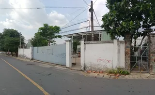 Roadside view of a gated manufacturing facility with a walled compound
