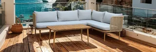 Gray outdoor corner sofa and wooden coffee table on a balcony