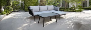 Gray outdoor sectional sofa and coffee table in a garden courtyard