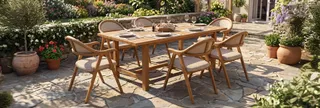 Wooden outdoor dining table and woven armchairs in a garden