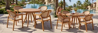 Round wooden outdoor dining table and woven chairs beside a pool