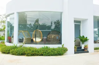 White furniture showroom exterior with hanging wicker chairs visible through the windows