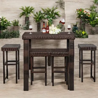Wicker bar table and stools arranged with plants, wine bottles and glassware