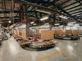 Large furniture factory floor with production stations and wooden panels.