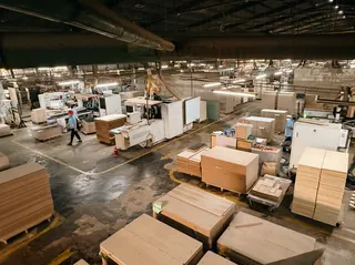 Wide factory interior with woodworking machinery, panels and production areas.
