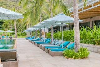 Poolside row of woven loungers with turquoise cushions