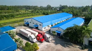 Aerial view of blue-roofed furniture factory buildings and delivery trucks