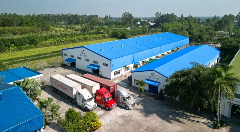 Aerial view of blue-roofed furniture factory buildings and delivery trucks