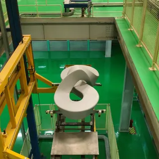 White molded furniture component suspended above factory equipment