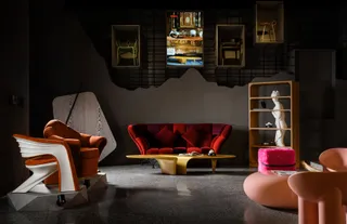 Collection of sculptural chairs, sofa, tables and shelving in a dark showroom