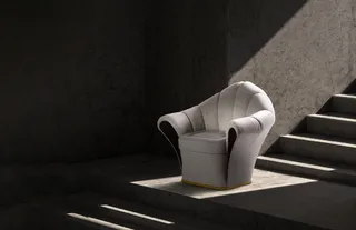 White upholstered armchair displayed on a sunlit platform beside stairs