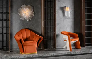 Orange armchairs displayed beneath decorative lights in a dark showroom setting
