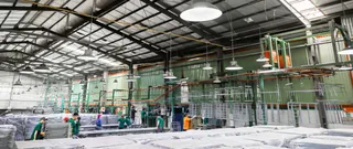 Workers and machinery inside a large metal furniture production floor