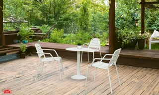 White outdoor table and chairs arranged on a wooden deck