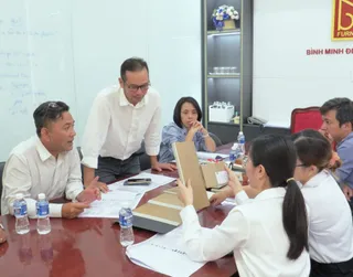 Staff members collaborating around a conference table with furniture samples and documents