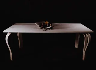 Wooden table with curved legs and a decorative bowl on a dark studio background