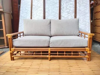 Front view of a bamboo two-seat sofa with gray cushions.