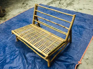 Bamboo-framed bench with woven seat photographed on a blue workshop floor.