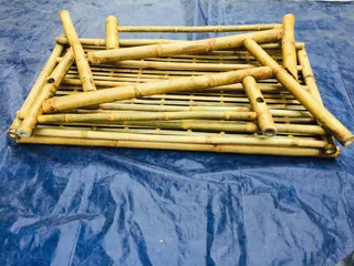 Stack of unfinished bamboo furniture components on a blue tarp.