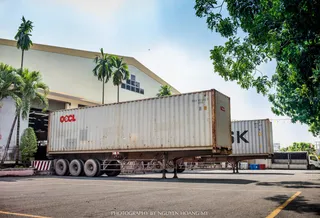 Industrial wood facility exterior with loaded shipping containers and truck