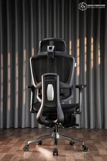 Black ergonomic office chair photographed against dark curtains
