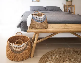 Woven baskets and rug beside a bamboo bench in a bedroom