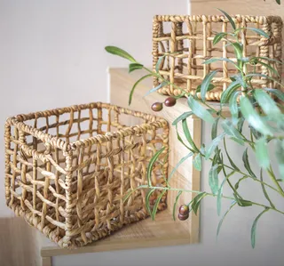 Two square woven storage baskets on a wooden shelf