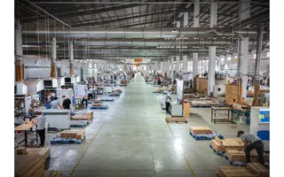Large furniture factory floor with production lines, machinery and workers
