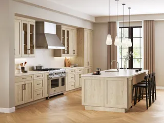 Light wood kitchen cabinets and island with appliances and bar stools