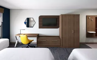 Hotel room with a desk, yellow chair, dresser, wardrobe and wall-mounted storage