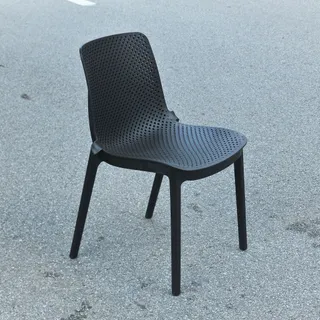 Black perforated plastic chair photographed outdoors