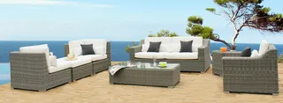 White-cushioned woven outdoor seating set on a wooden deck