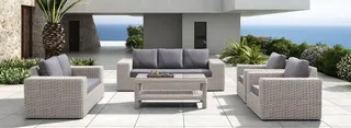 Light woven outdoor sofa set with armchairs and coffee table on a patio