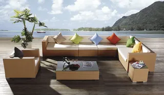 Tan woven outdoor sectional sofa with colorful cushions and coffee table